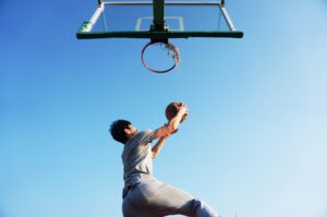 Basketballer taucht mit Ball unter dem Korb durch
